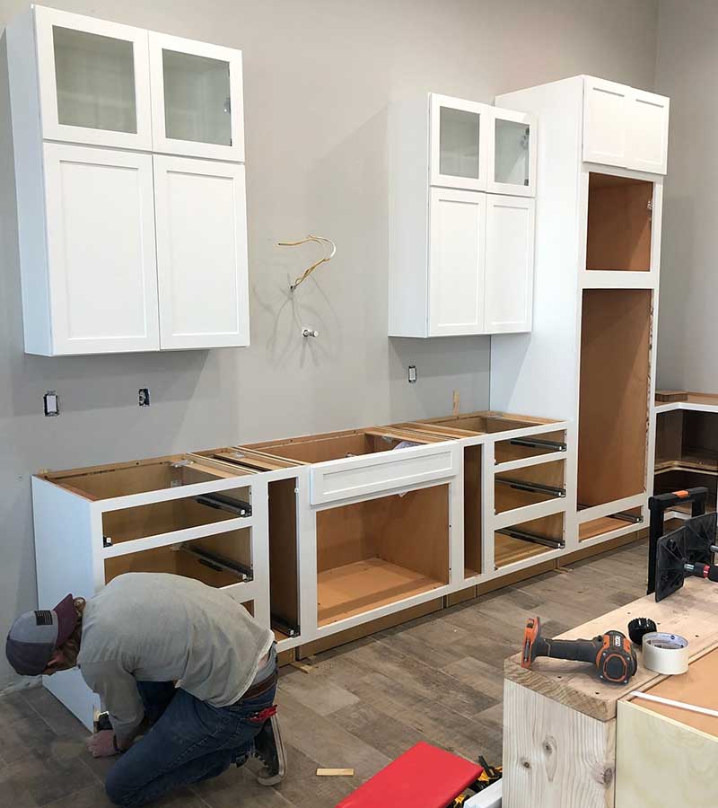 Kitchen island with a white and grey granite waterfall edge, tan cabinets and a skink