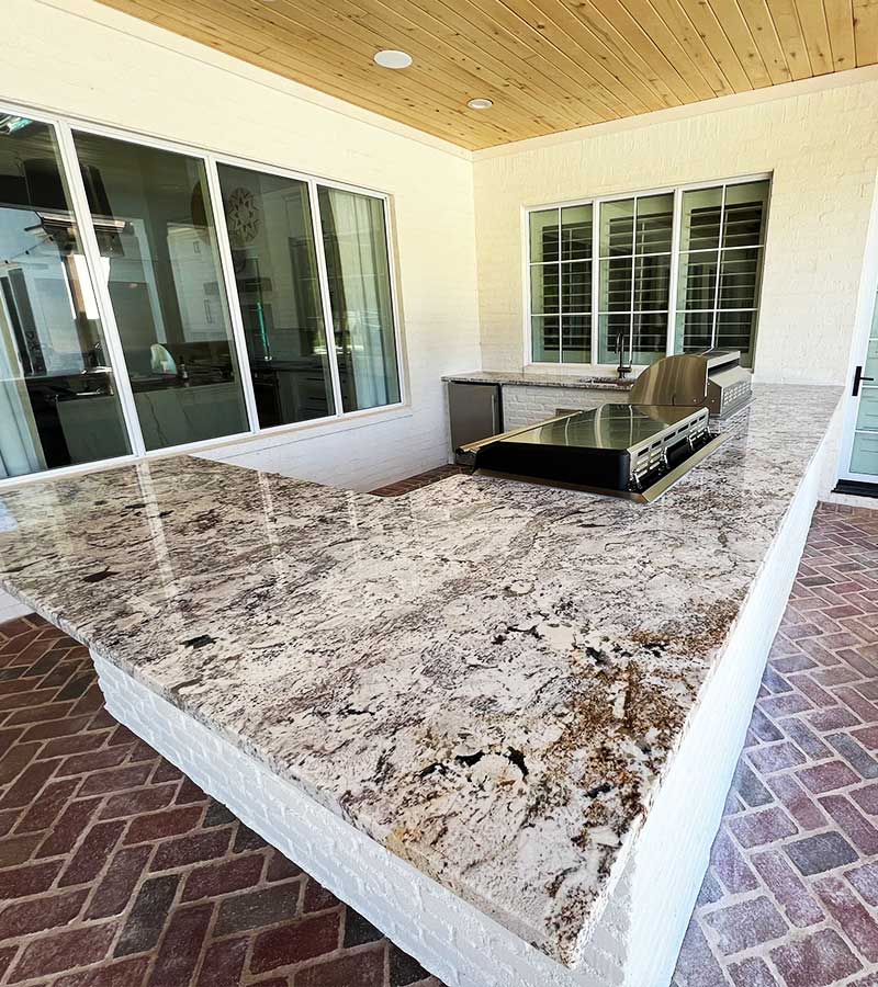 Large marble countertop outside with range top and grill built in.